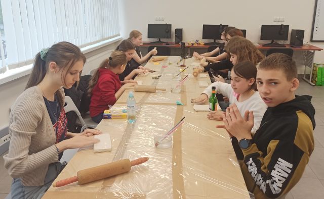 młodzież siedzi przy stołach zasłoniętych folią, na stołachglina i wałki