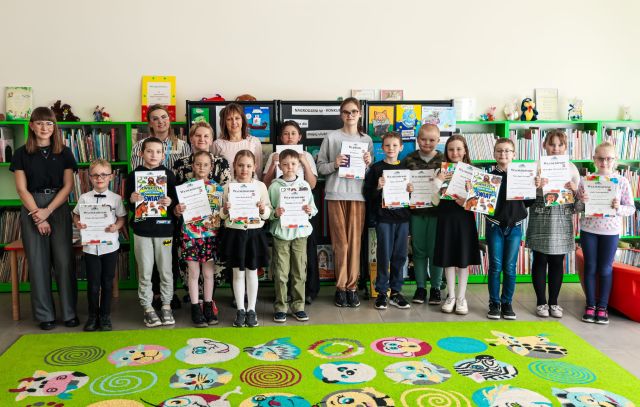 laureaci konkursu pozują do zdjęcia z dyplomami i książkami