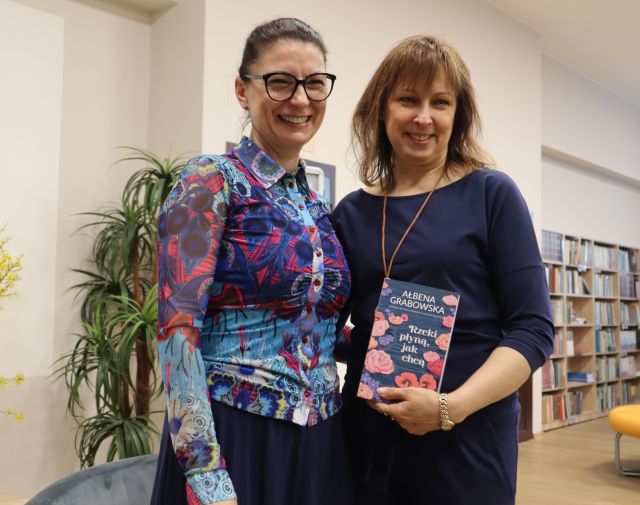 dyrektorka biblioteki z książką i autorka pozują do zdjęcia