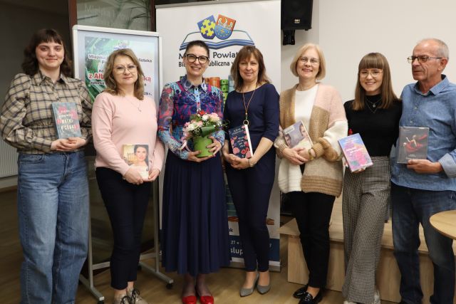 4 bibliotekarki i dyrektorka z książkami, mężczyzna i autorka pozyją do zdjęcia