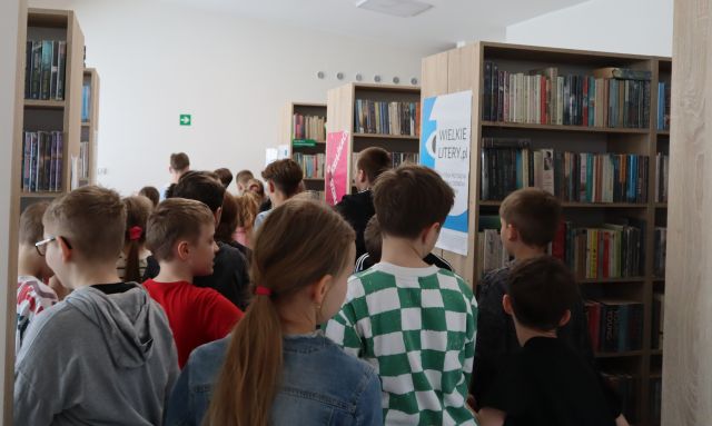 dzieci pomiędzy regałami z książkami w bibliotece