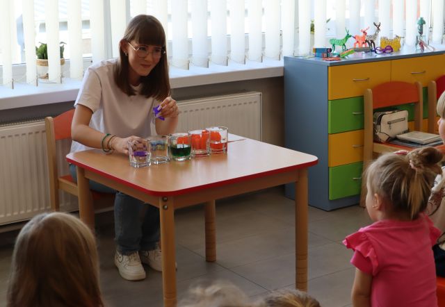 bibliotekarka przy stole robi eksperyment z farbkami i papierkami