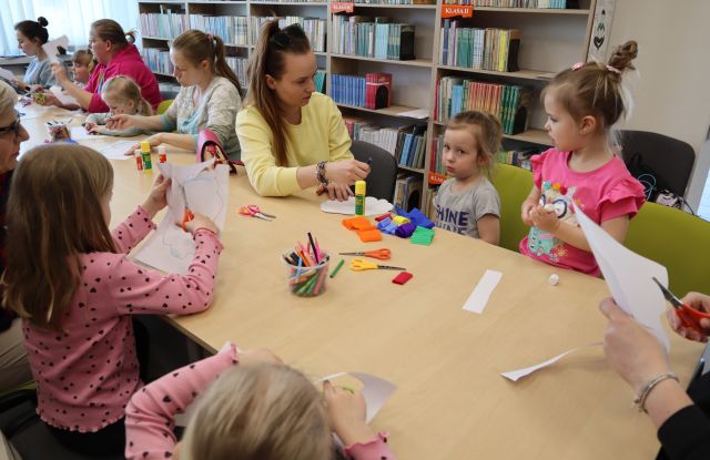 dzieci z rodzicami siedzą przy stołach, na stołach kartki, nożyczki, kleje