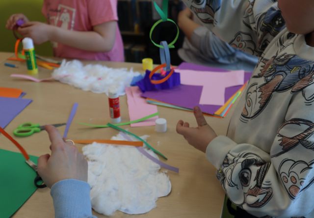 dłonie wycinające z kartek chmurki i klejące watę