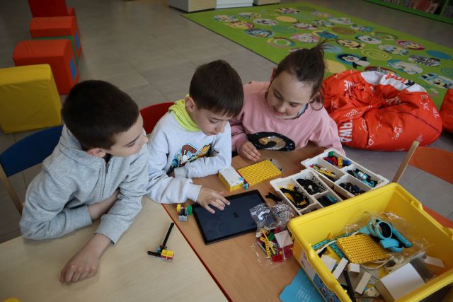 dziewczynka i dwóch chłopców budują z klocków LEGO