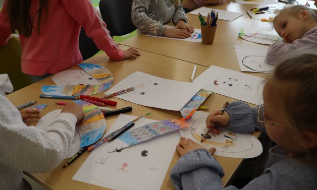 na stołach leżą pomalowane w jajka kartki, przy stołach siedzą dzieci