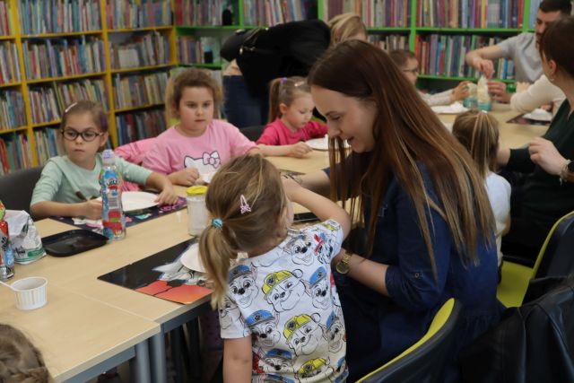 dzieci i rodzice siedzą przy stołach, na stołach mąka, pianka do golenia i tacki