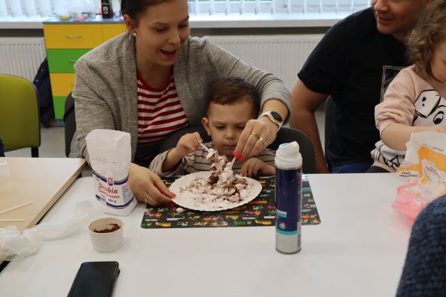 chłopiec z mamą mieszają masę na papierowym talerzyku