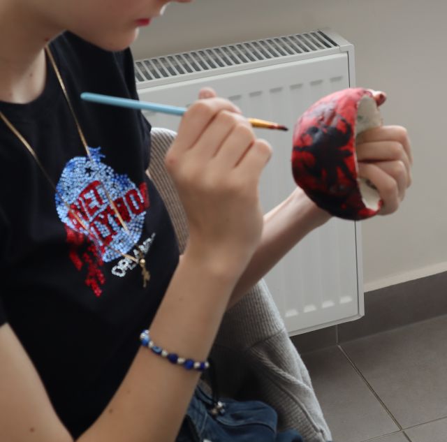 dłonie z pędzelkiem i miska z gliny