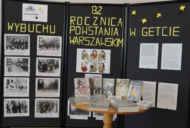 wystawa prezentująca wybuch powstania w getcie warszawskim, na wystawie artykuły, zdjęcia i książki na stoliku