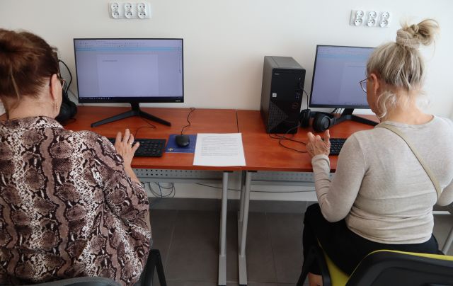 dwie osoby siedzą przy komputerach