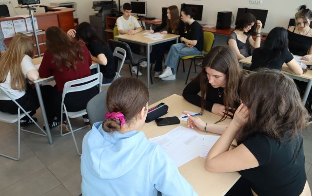 przy stolikach w sali komputerowej siedzi młodzież, rozwiązują zadania