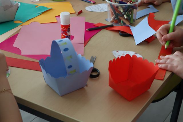 na stoliku dwa papierowe koszyczki i kolorowe kartki