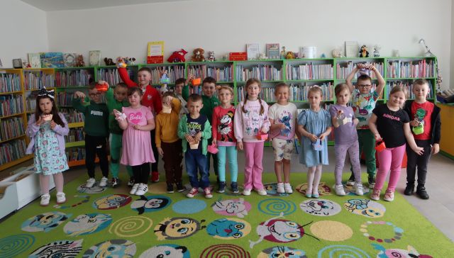 przedszkoalki pozują do zdjęcia na tle regałów z książkami