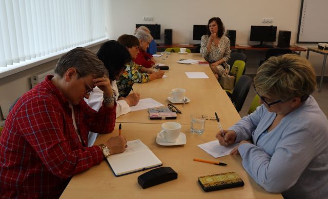 seniorki siedzą przy stołach i piszą na kartkach