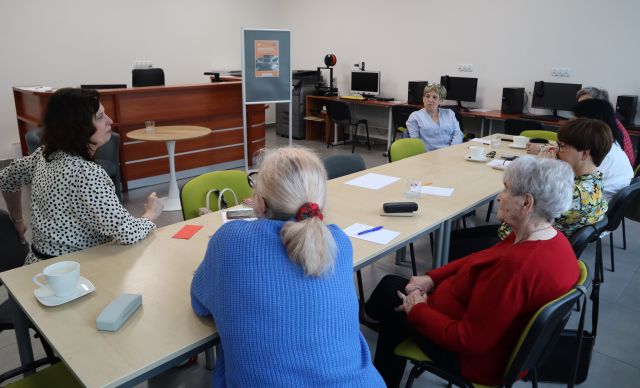 seniorki siedzą przy stołach, na stołach leżą kartki