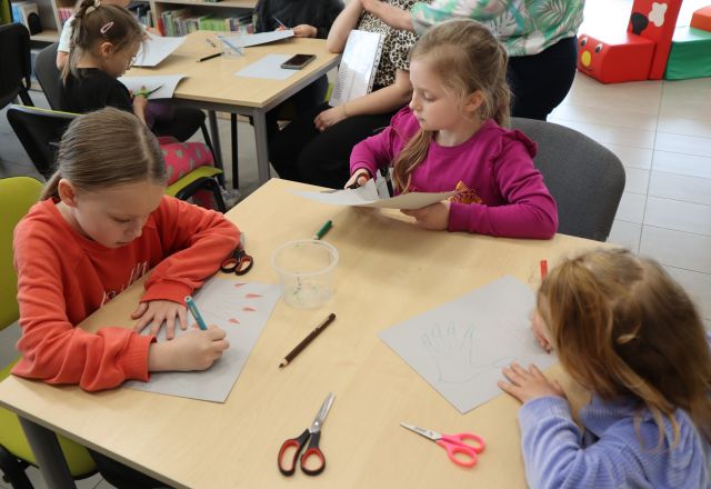 trzy dziewczynki siedzą przy stoliku i rysują na kartkach