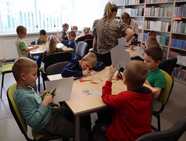 przedszkolaki soedzą przy stolikaci, rysują, wycinają i kleją