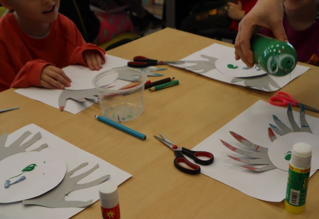 na stole kartki, wycięte dłonie i nożyczki