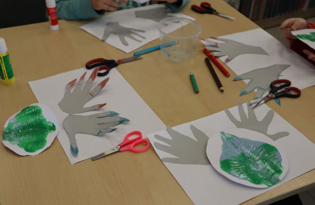 na stole kartki, wycięte dłonie i nożyczki