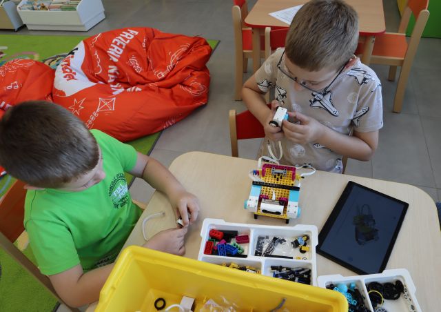 dwóch chłopców siedzi przy stoliku z klockami LEGO