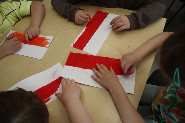 biało-czerwone kartki i dłonie dzieci z kredkami