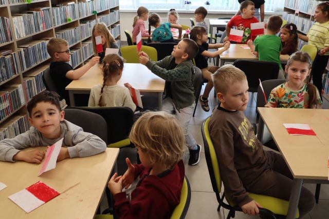 przedszkolaki siedzą przy stolikach, na stolikach białe kartki