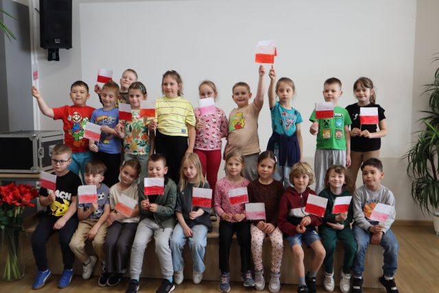 przedszkoalki pozują do zdjęcia na scenie z flagami Polski