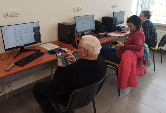 pan i dwie kobiety siedzą z telefonami komórkowymi przed komputerami