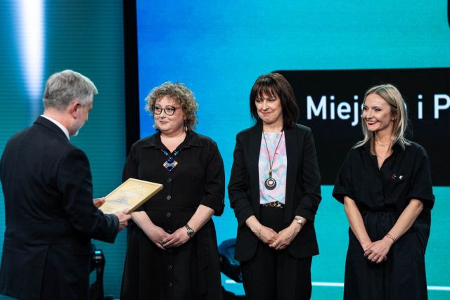 na telewizyjnej scenie 3 kobiety, przed nimi mężczyzna z dyplomem 