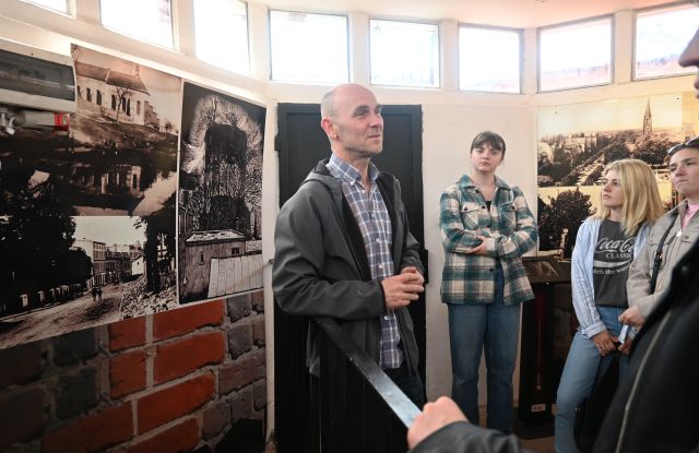 mężczyzna opowiada kobietom, sala wystawowa