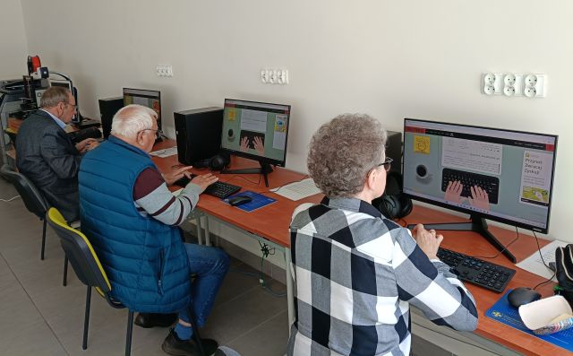 dwóch mężczyzn i kobieta siedzą przed komputerami