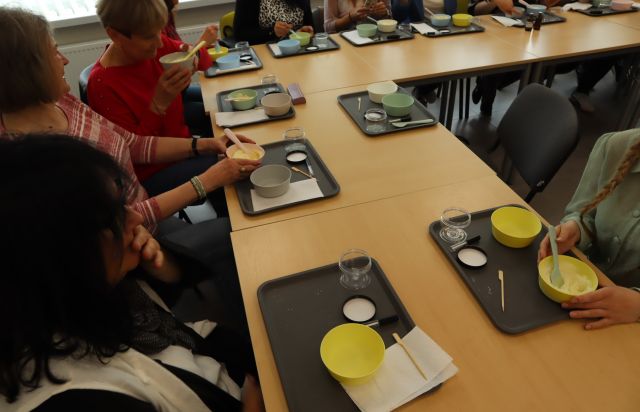 na stołąch plastikowe tacki i talerzyki oraz dłonie uczestniczek warsztatów