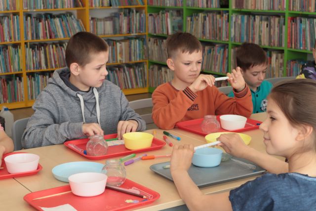 na zdjęciu chłopcy z pipetkami, w tle regały z książkami
