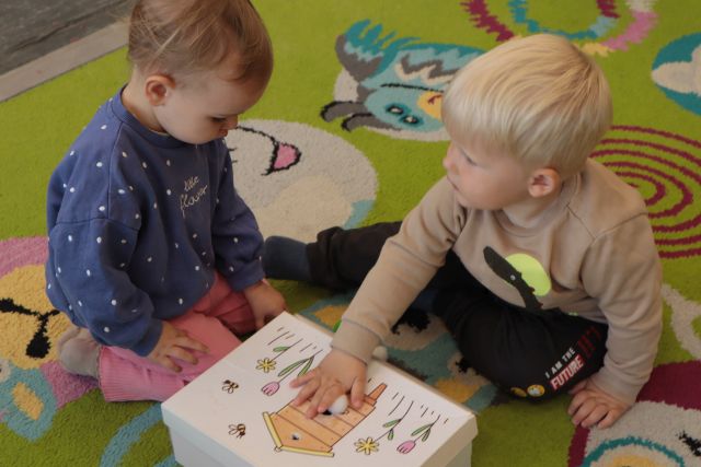 dwóch chłopców bawi się drewnianym pudełkiem