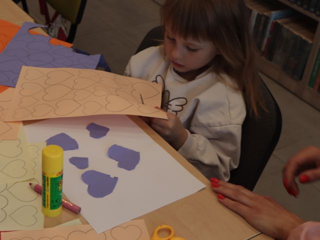 dziewczynka wycina z kartki serduszka