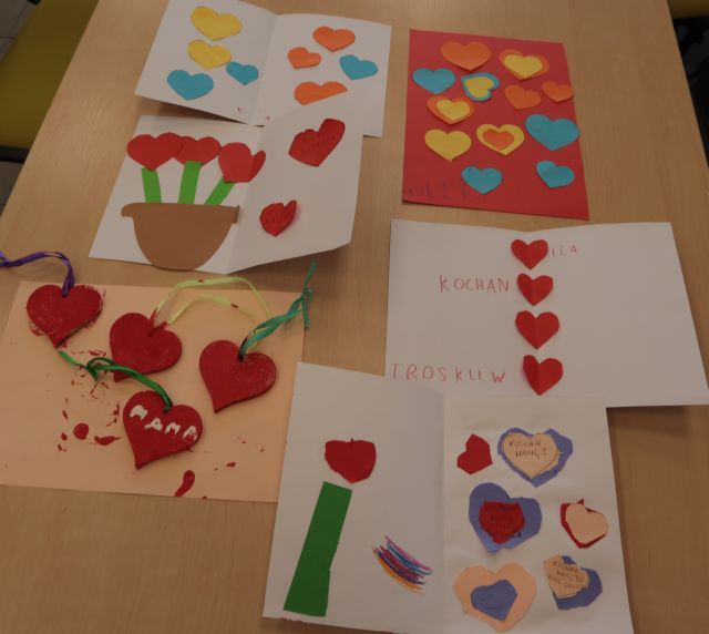prezentacja rozłożonych na stole prac - laurek dla mamy i drewnianych serduszek