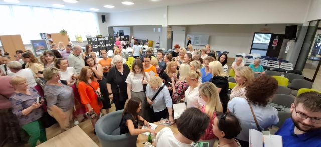 uczestniczki spotkania zgromadzeni wokół aktorki podpisującej książkę