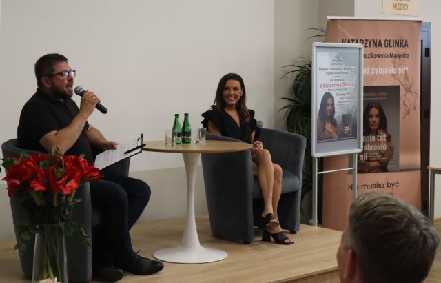 mężczyzna i kobieta z mikrofonami siedzą na fotelach