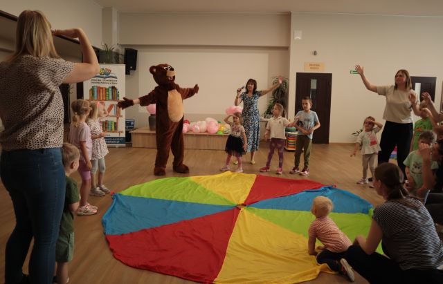 dzie z rodzicami i misiem bawią się wokół chusty animacyjnej