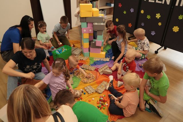 dzieci z rodzicami bawią się sensorycznie siedząc na chuście animacyjnej