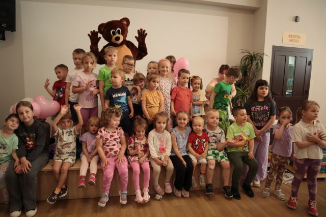 dzieci pozują do zdjęcia z misiem