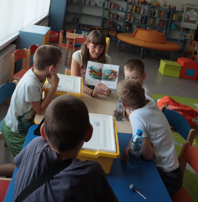 4 chłopców siedzi przy stoliku z klockami Lego