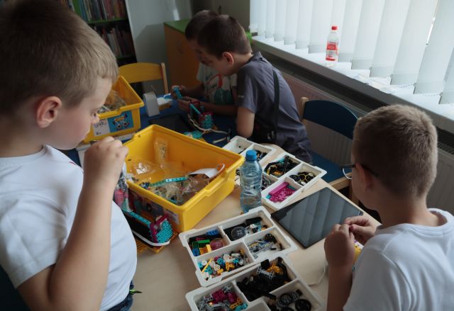 3 chłopcó buduje z klocków Lego