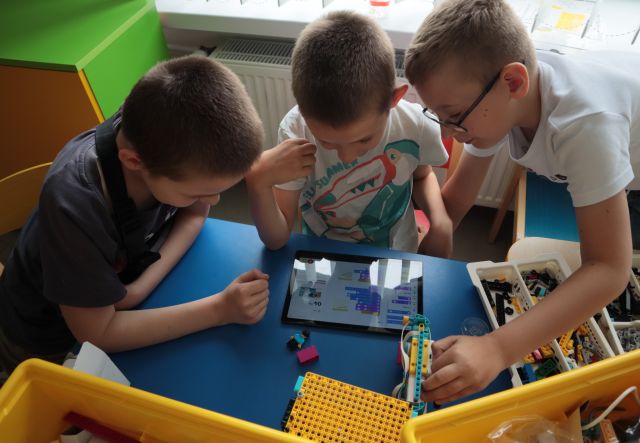 3 chłopcó pochylonych nad tabletem