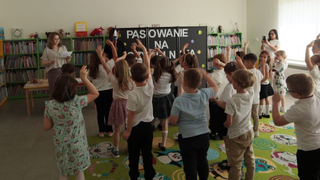 przedszkolaki stoją z podniesionymi prawymi rękoma w górę