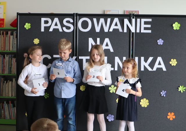 4 dzieci stoi z kartkami z cyframi