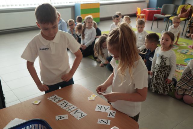 dziewczynka i chłopiec ukłdają z karteczek z literkami słowo książka i katalog