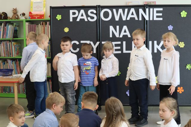 dzieci stoją w rzędzie przed bibliotekarką