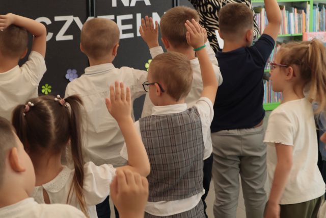 na zdjęciu dzieci z podniesionymi do góry prawymi rękami